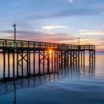 Long wooden pier over Mobile Bay during a colorful sunset in Daphne, Alabama.
